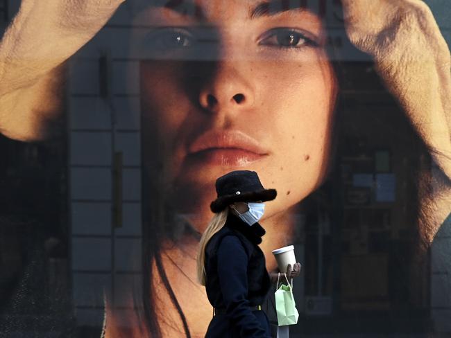 A woman wearing a protective mask walks past a store window in Munich. Germany will extend coronavirus restrictions into 2021. Picture: AFP