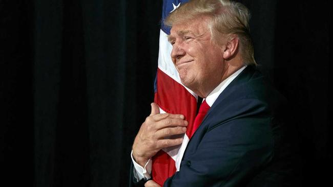 Republican presidential candidate Donald Trump hugs an American flag as he arrives to speak to a campaign rally, Monday, Oct. 24, 2016, in Tampa, Fla. (AP Photo/ Evan Vucci). Picture: Evan Vucci