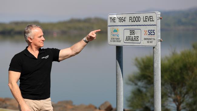 Kerry Plowright, of Aeeris, points to a sign next to the Tweed River showing the flood level in 1954 as a result of the 'Great Gold Coast Cyclone'