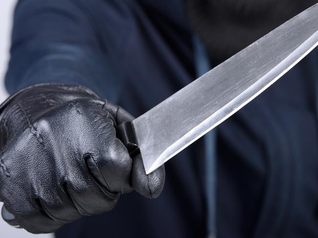 Masked man aims with knife. on gray background. Robbery, crime, knife generic