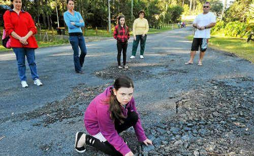 Kristy Goldsby and neighbours check out Avocado Heights potholes. Picture: Bruce Thomas