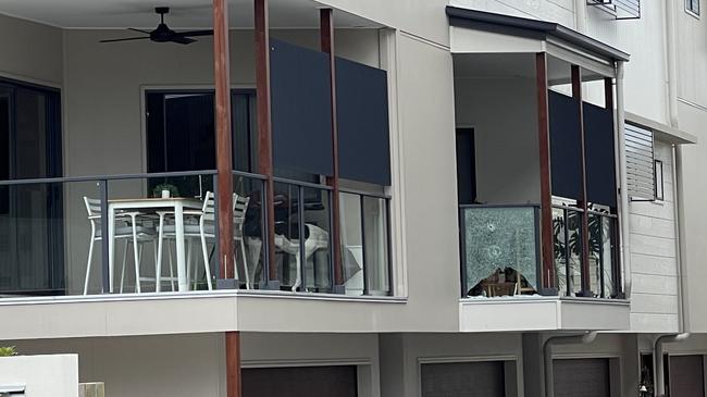 Residents stand under a shattered glass balcony window at a Morningside townhouse complex. Picture: Matthew Johnston