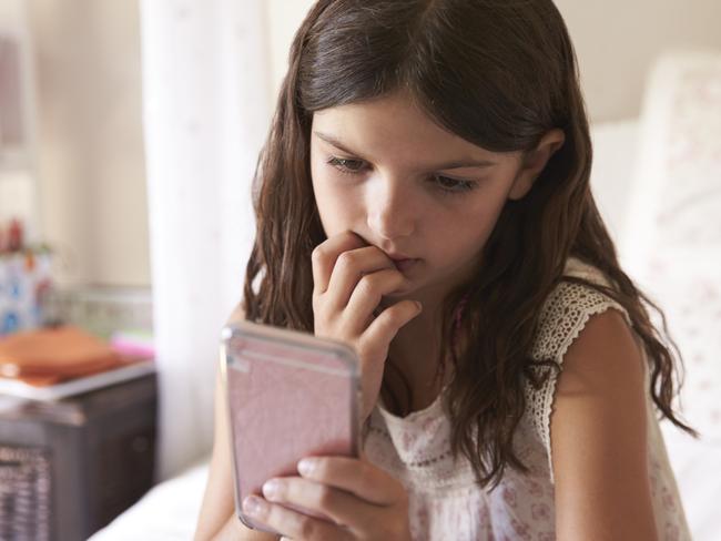 Young Girl In Bedroom Worried By Bullying Text Message