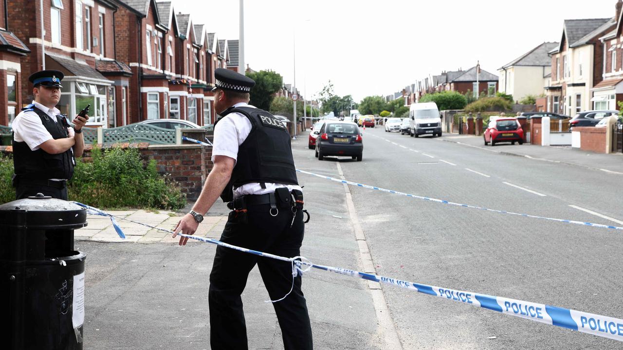 Police officers stand guard behind a cordon on Hart Street in Southport, northwest England. (Photo by Darren Staples / AFP)