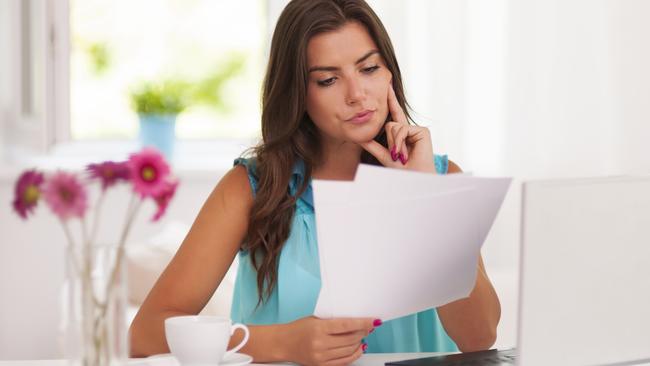 A woman with her computer and bank statements sitting at a desk. She is also analysing her superannuation statement. Picture: iStock.