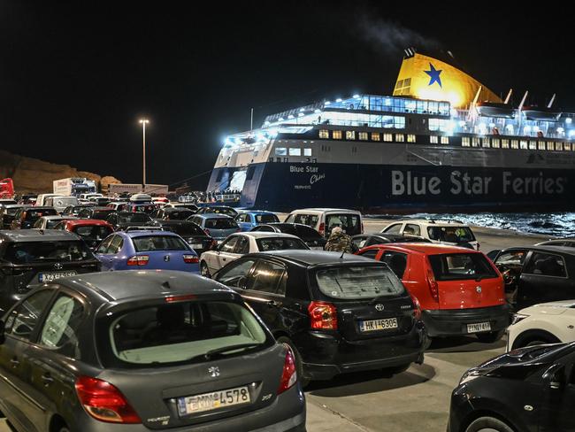 Cars queue to embark a ferry as people leave on the Greek Island of Santorini. Picture: AFP