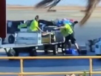 A Qantas baggage handler has been stood down after he was caught violently hauling passengers’ luggage onto a trailer. Source: Rohan Allen