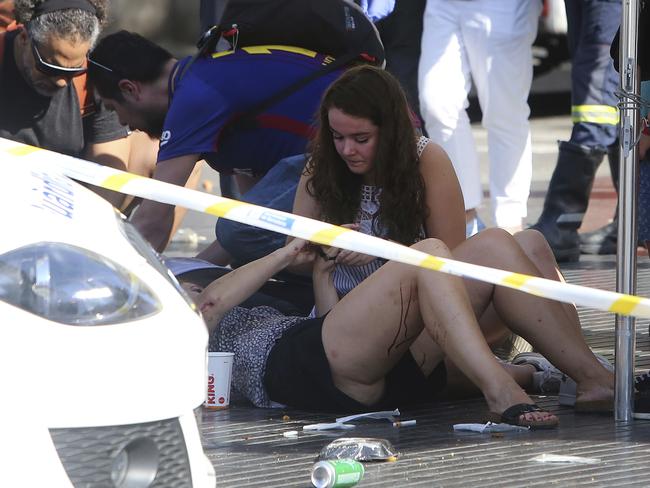 Injured people are treated in Barcelona, Spain, after a white van jumped the sidewalk in the historic Las Ramblas district, crashing into a summer crowd of residents and tourists. Picture: AP Photo/Oriol Duran