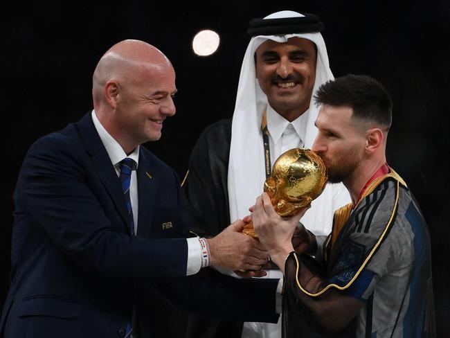 Argentina's forward #10 Lionel Messi kisses the World Cup trophy as FIFA President Gianni Infantino and Qatar's Emir Sheikh Tamim bin Hamad al-Thani look on. Picture: AFP