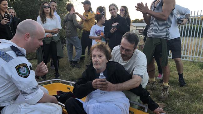 Wagner Fernandes, 66, a is comforted by friends, relatives and emergency services personnel, just moments after he was found on a creek bank at the rear of an abandoned semirural property on Wattle Rd Ingleside. Picture: Jim O'Rourke