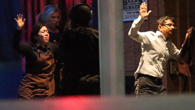 Hostages run to safety during a cafe siege in the central business district of Sydney , Australia, Tuesday, Dec. 16, 2014. A swarm of heavily armed police stormed the cafe in the heart of downtown Sydney early Tuesday, ending a siege where a gunman had been holding an unknown number of people hostage for more than 16 hours. A police spokesman confirmed "the operation is over," but would not release any further details about the fate of the gunman or his remaining captives. After a flurry of loud bangs, police swooped into the Lindt Chocolat Cafe shortly after five or six hostages were seen running from the building. (AP Photo/Rob Griffith)