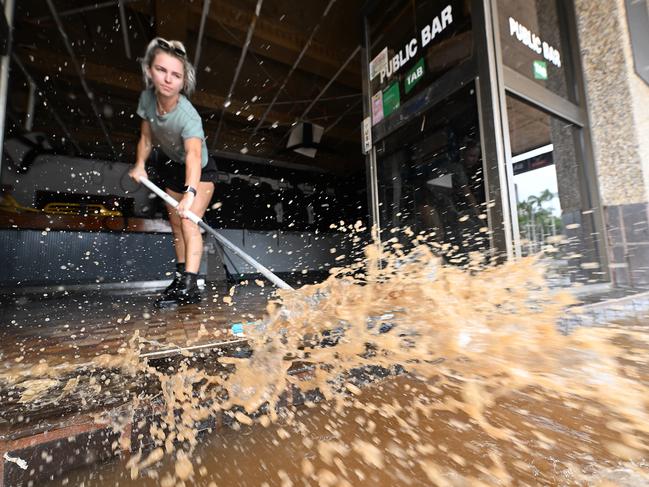 Wading through the receding flood waters, Laani Winkler helps friend Kylie Gilmore clean her flood ravaged pub in Lismore. Picture: Lyndon Mechielsen
