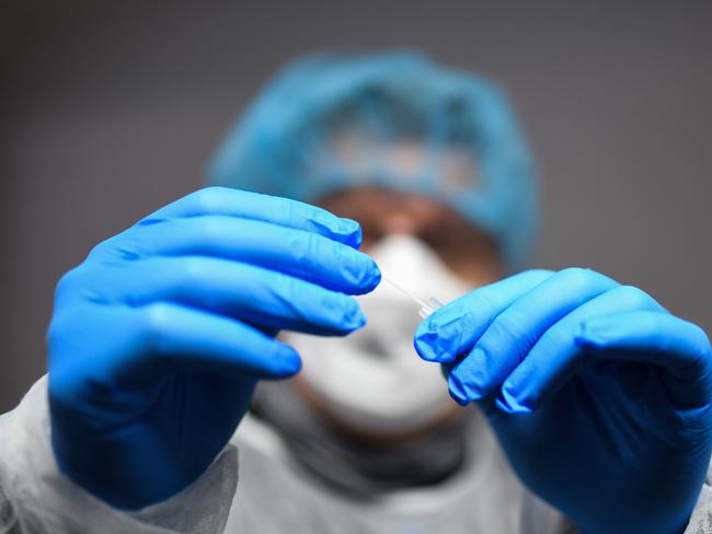 A medical assistant wearing protective mask, gloves and garment processes a sample from a rapid antigen test. Picture: AFP