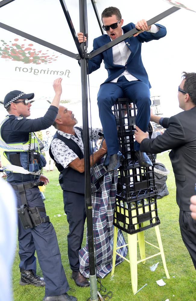 Racegoers try to climb onto an umbrella using crates at the end of the day. Picture: Tracey Nearmy/AAP