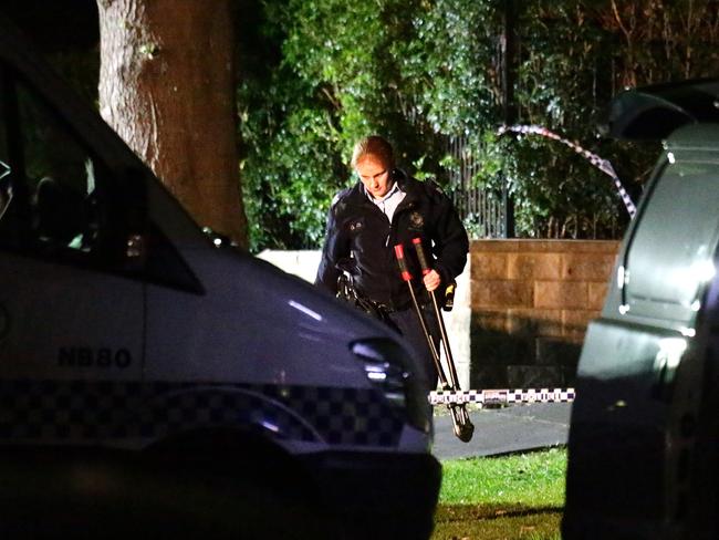 A police officer carries a pari of bolt cutters as crews sift through the Marnique family home. Picture: Bill Hearne