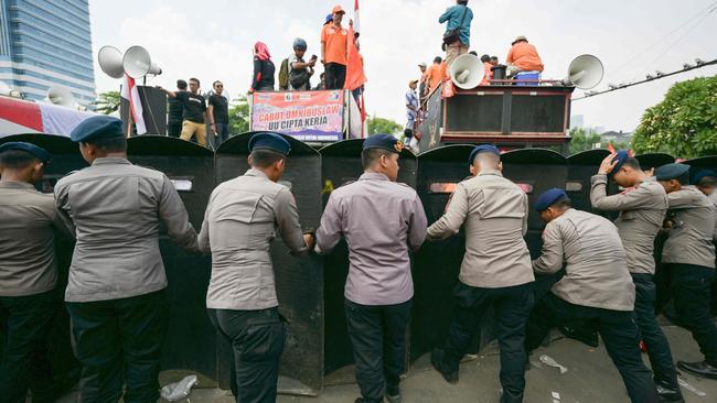 Police form a barricade with their shields to keep protesters at bay outside Jakarta’s House of Representatives building. Picture: AFP