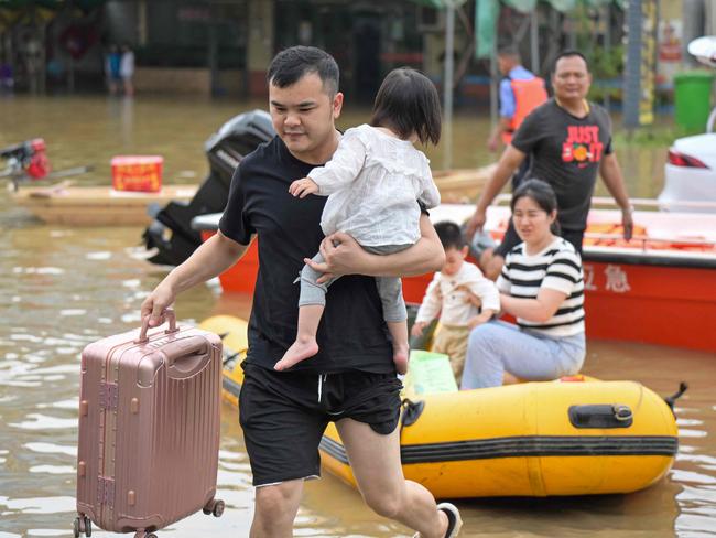 Residents wade through floodwaters after being evacuated from a flooded area following heavy rains in Qingyuan. Picture: CNS / AFP