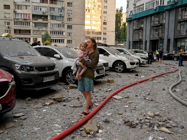 A local resident carries a baby outside a 24-storey building partially destroyed as a result of missiles strike in Ukrainian capital of Kyiv early on June 24. Picture: Sergei SUPINSKY / AFP