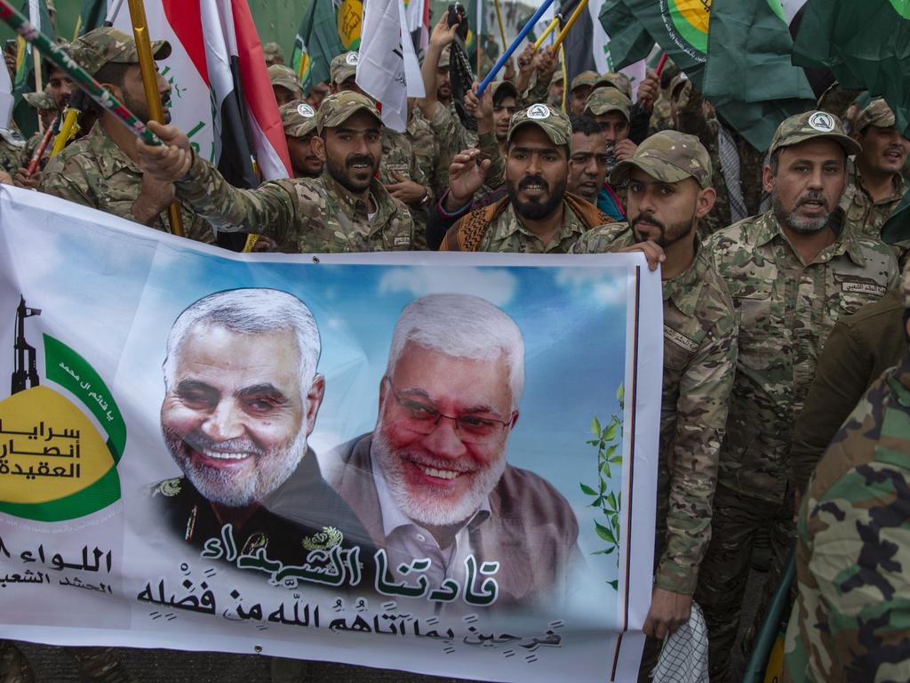 Iraqi militiamen march and chant anti U.S. slogans while carrying a picture of Soleimani, left and Abu Mahdi al-Muhandis, with Arabic that reads "our martyr leaders," during the funeral of Iran's top general Qassem Soleimani and deputy commander of Iran-backed militias. Picture: Nasser Nasser