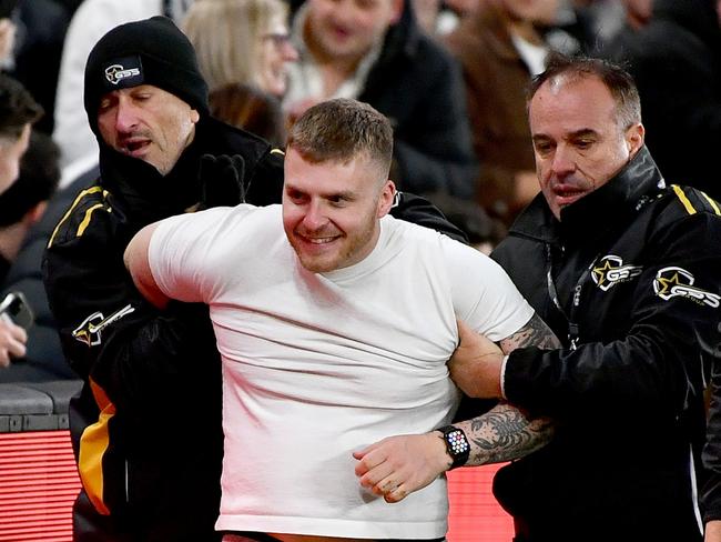 MELBOURNE, AUSTRALIA - JUNE 16: A pitch invader is escorted from the ground by security during the round 14 AFL match between North Melbourne Kangaroos and Collingwood Magpies at Marvel Stadium, on June 16, 2024, in Melbourne, Australia. (Photo by Josh Chadwick/AFL Photos/Getty Images)