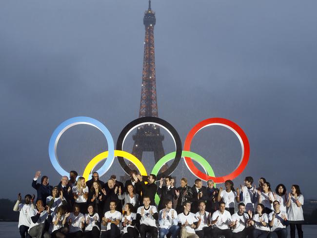 Paris officials pose in front of a display showing the Olympic rings on Trocadero plaza that overlooks the Eiffel Tower.