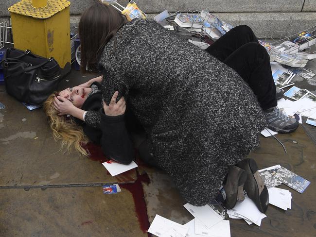 A passerby comforts an injured woman lying on the pavement after Khalid Masood drove his car into pedestrians killing four in addition to a police officer at Westminster Bridge in London, Britain, March 22, 2017. Picture: Toby Melville/Reuters/World Press Photo