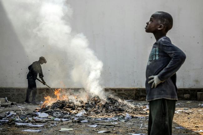 A man sifts through the smoldering remains of boxes and materials left behind by looters in Bukavu