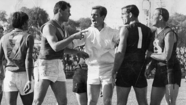 West Torrens’ Neil Hawke points at South Adelaide’s captain-coach Neil Kerley, right, with umpire Ken ‘KG’ Cunningham in the middle in 1966 during an SNFL match at Adelaide Oval.