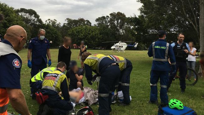 Emergency helicopter and ambulance paramedics attend to a boy, 12, who fell from his bicycle on a jump ramp in a reserve at Mona Vale. Picture: CareFlight