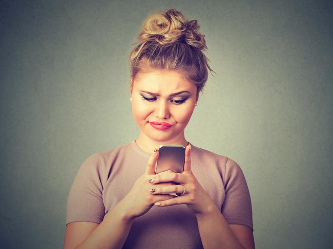 Closeup portrait upset sad skeptical unhappy serious woman talking texting on phone displeased with conversation isolated gray background. Negative human emotion face expression feeling reaction