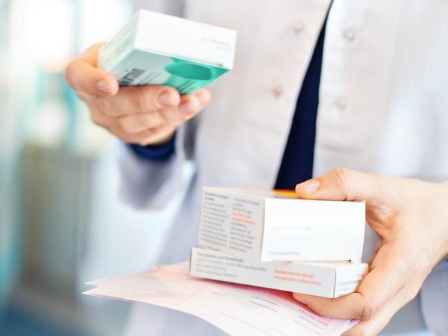 Closeup of pharmacist's hands taking medicines from shelf at the pharmacy