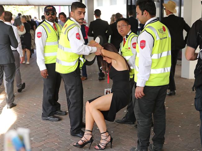 A female racegoer is escorted from the racetrack by security at this year’s Derby Day carnival at Flemington. Picture: Scott Barbour/Getty Images.
