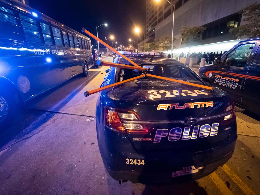 A police car is vandalised during rioting. Picture: John Amis/Agence France-Presse/ AFP