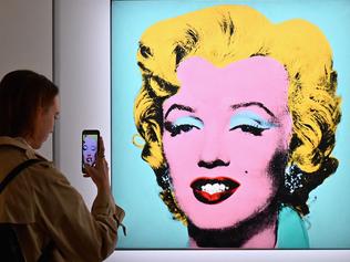 (FILES) In this file photo taken on April 29, 2022 a woman takes a photo of Andy Warhol's 'Shot Sage Blue Marilyn' during Christie's 20th and 21st Century Art press preview at Christie's New York in New York City. - An iconic portrait of Marilyn Monroe by American pop art visionary Andy Warhol went under the hammer for a record $195 million on May 9, 2022 at Christie's, becoming the most expensive 20th century artwork ever sold at public auction. "Shot Sage Blue Marilyn," produced in 1964 two years after the death of the glamourous Hollywood star, sold for exactly $195.04 million, including fees, in just four minutes in a crowded room at Christie's headquarters in Manhattan. (Photo by Angela Weiss / AFP)