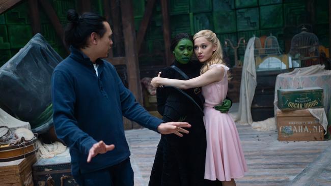 Director Jon M. Chu with Cynthia Erivo (as Elphaba) and Ariana Grande (as Glinda) on the set of Wicked.