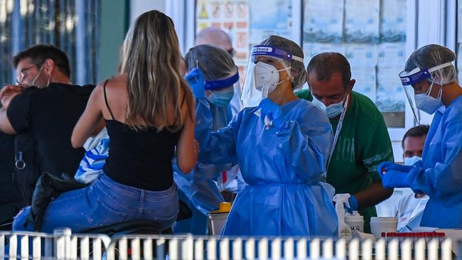 Holidaymakers on a motorbike returning from Sardinia by ferry undergo a compulsory drive-through swab test at the port of Civitavecchia, northwest of Rome. Picture: AFP