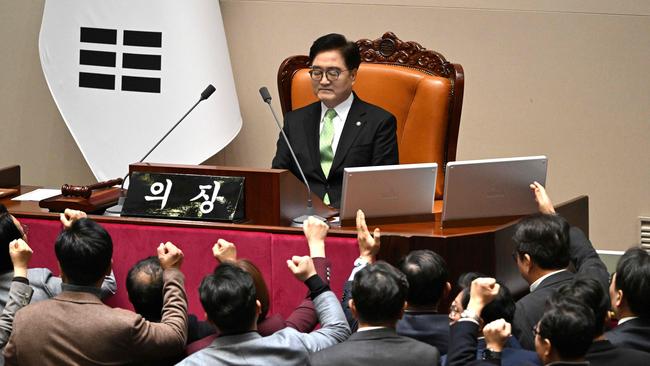 TOPSHOT - South Korea's ruling People Power Party lawmakers (bottom) argue to National Assembly Speaker Woo Won-shik (C top) during the plenary session for the impeachment vote of acting president Han Duck-soo at the National Assembly in Seoul on December 27, 2024. (Photo by JUNG YEON-JE / AFP)