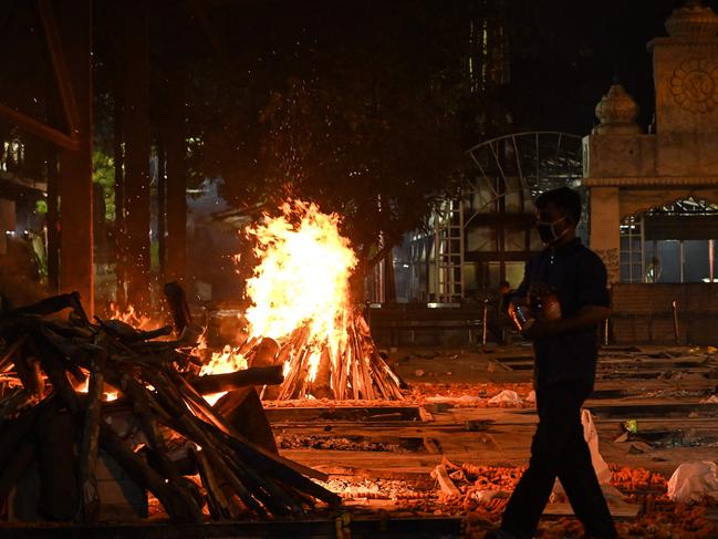 A crematorium staff walks past a pyre of a Covid-19 victim at Nigambodh Ghat Crematorium, on the banks of the Yamuna river in New Delhi. Picture: AFP