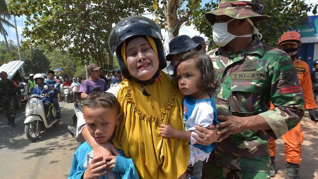 A woman cries next to her children shortly after the aftershock, which caused panic among evacuees sheltering after Sunday’s devastating earthquake. Picture: Adek Berry/AFP