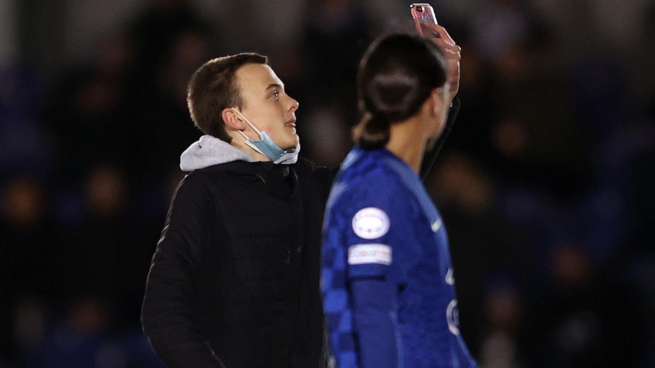 The pitch invader takes a selfie in front of Sam Kerr before the Australian soccer star lines him up and bumps him over. Picture: Getty Images