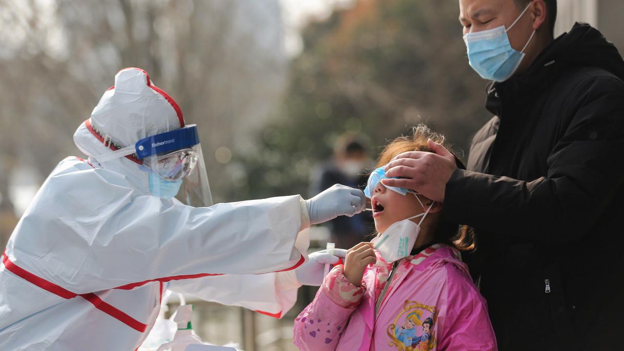 A medical staff member collects sample from a girl for a nucleic acid test for coronavirus at a residential area in Wuhan in China's central Hubei province. Picture: STR/AFP