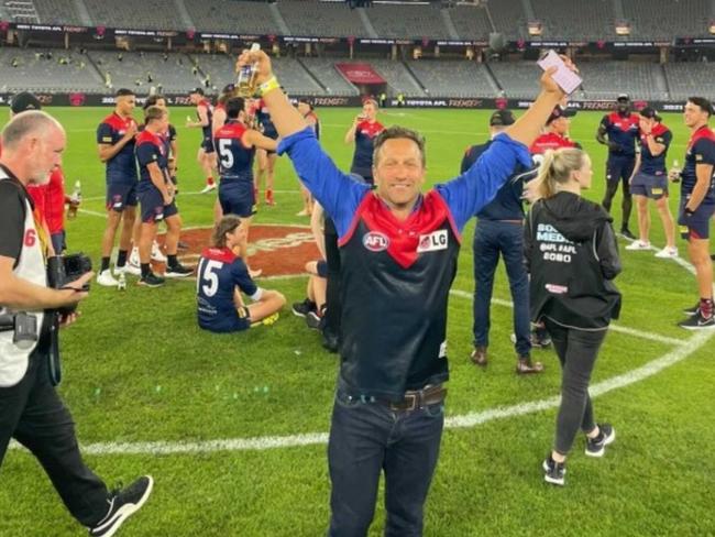 Hayden Burbank on the ground at Optus Stadium after the Demons won the Grand Final.