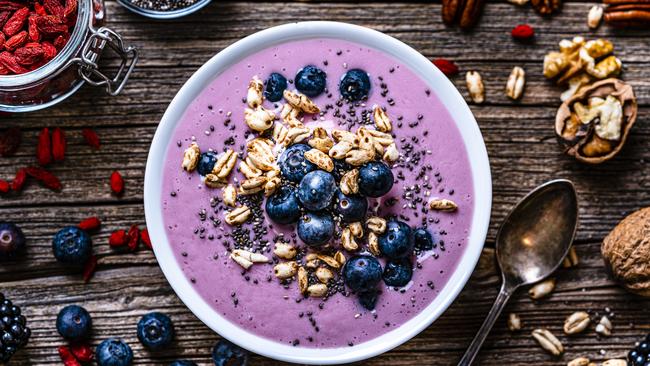 Healthy eating: overhead view of a mixed berries smoothie bowl with oat, chia seeds and nuts shot on rustic wooden table. Blackberries, blueberries, goji berries, pecan, walnuts and chia seeds are around the smoothie bowl. High resolution 42Mp studio digital capture taken with Sony A7rII and Sony FE 90mm f2.8 macro G OSS lens