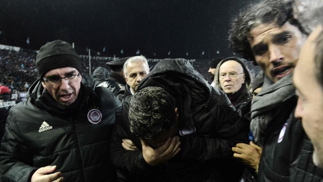 Olympiakos' Spanish coach Oscar Garcia Junyent (C) reacts after being hit in the face by a toilet roll, thrown by a Paok fan