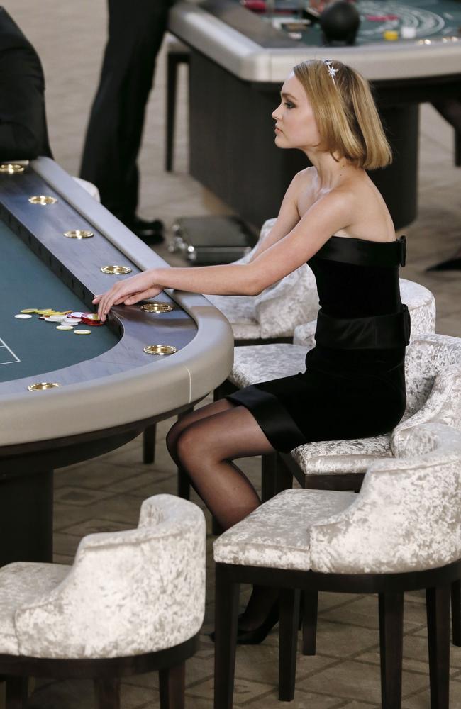 Lily-Rose Depp sits at a casino table during the Chanel show. Picture: AFP