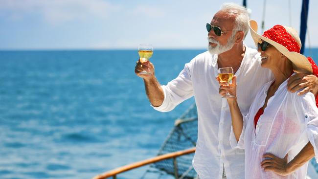 Closeup side view of mid 60's couple enjoying a sailing cruise during  summer vacation at seaside. They are leaning on deck railing and enjoying the view of the sea and horizon. rich wealthy generic