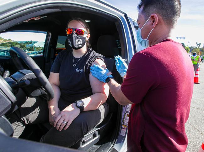 Doctor Richard Dang (R), Assistant professor USC School of Pharmacy, administers a Covid-19 vaccine to Ashley Van Dyke as mass-vaccination of healthcare workers takes place at Dodger Stadium on January 15, 2021 in Los Angeles, California. (Photo by Irfan Khan / POOL / AFP)