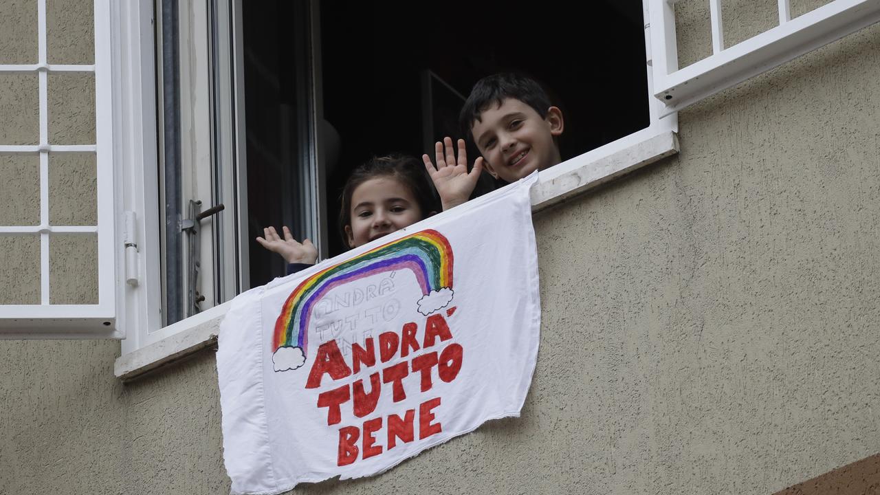 Francesco and Greta wave from their apartment window above a banner in Italian that means: "Everything will be all right” in Rome on March 13, 2020. Picture: AP