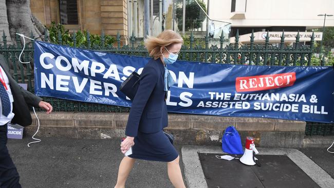 Queensland Chief Health Officer Dr Jeannette Young walks past an anti-euthanasia protest outside Parliament House in Brisbane. Picture: NCA NewsWire / Dan Peled