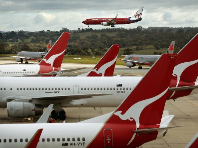 A Virgin Australia 737 lands amongst QANTAS and Jetstar aircraft at Melbourne's Tullamarine Airport.